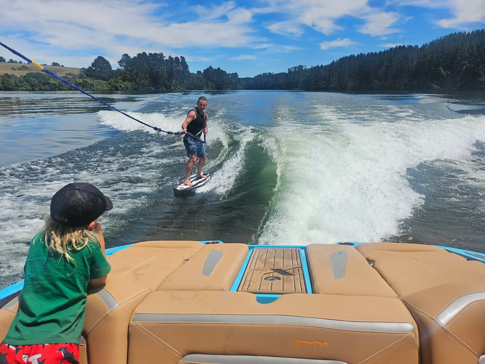 Wakesurfer behind the boat beneath blue skies